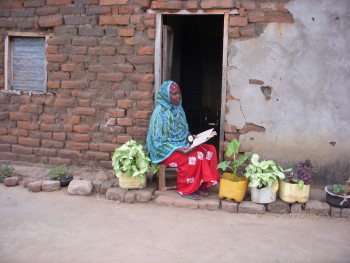 Woman in Tanzania reads while holding a solar-powered lantern purchased from Solar Sister. Solar lanterns, like this one, provide light to women and their families who were previously living in darkness. 