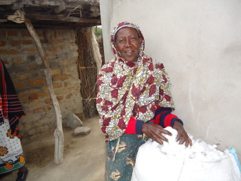 A Solar Sister customer weighs out the cotton she has been able to harvest with the help of her solar lamp. She appreciates the light in her house as well as the decreased danger of her cotton catching fire now that she uses a solar lamp rather than kerosene lamps.