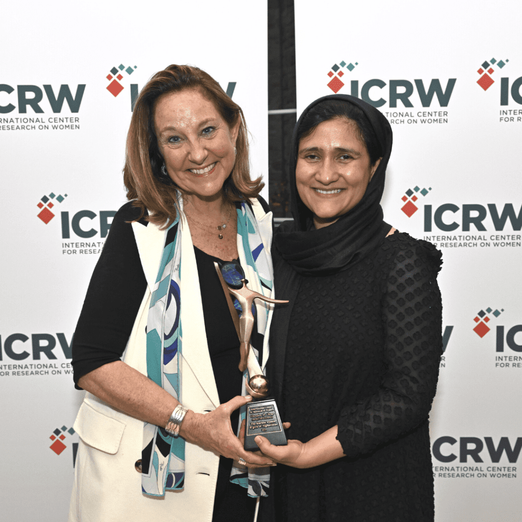 Peggy Clark, ICRW CEO, handling a Champions for Change award to 2022 recipient Shabana Basij-Rasikh.